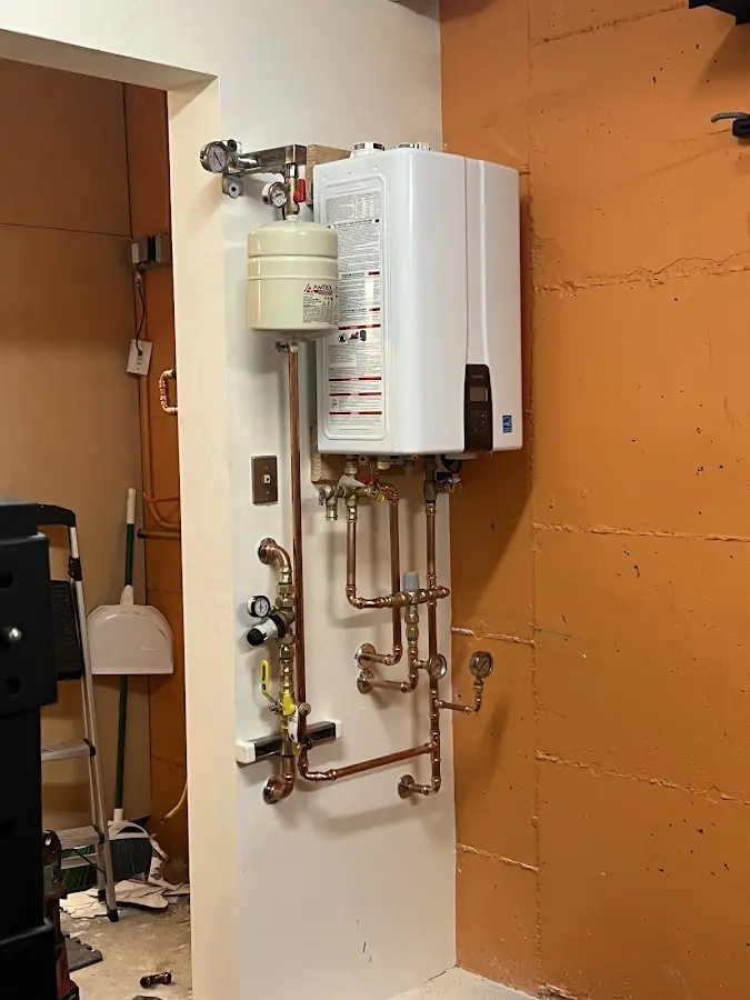 Plumbing technician inspecting water heater connections in Henrietta